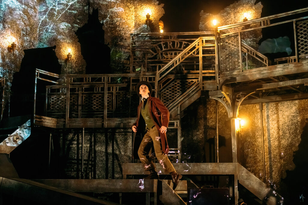 A warm glow on stage, Jonathan looks out in fear as he runs up the stairs. 